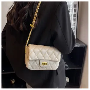 Detail of cream quilted crossbody bag with gold twist lock and chain strap on model