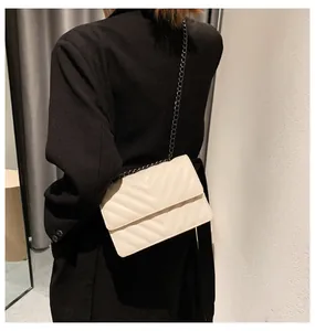 Detailed view of beige V-quilted flap bag with black chain strap on black blazer