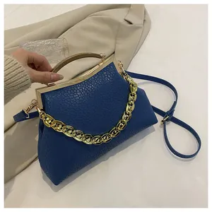 Detailopname van donkerblauwe handtas met steentextuur en goudkleurige kliksluiting
