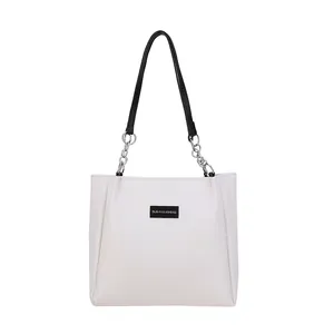 Elegante borsa tote beige trapuntata con tracolla a catena argento ed etichetta del marchio