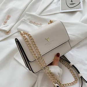 Minimalist beige crossbody bag with gold deer head emblem and metal chain strap