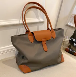 Large gray nylon tote bag with brown leather handles and base reinforcement pads