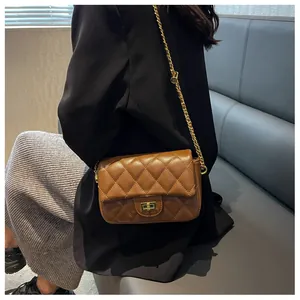 Minimalist brown quilted leather crossbody bag with gold chain strap worn by a model