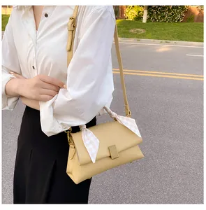 Détail du sac à bandoulière beige avec fermoir doré et foulard en soie sur l'anse