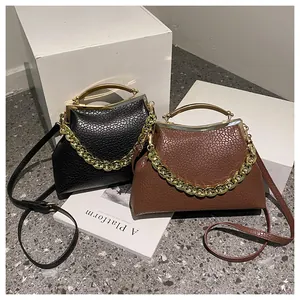 Detail van leren crossbodytassen met gouden metalen handgrepen en lychee-textuurpatroon