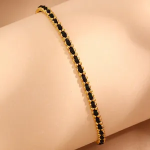 Macro detail of 18k gold beads woven into a black rope bracelet on a soft pink stand