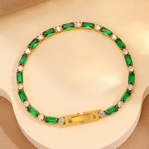 Gros plan du bracelet tennis doré orné de gemmes vert émeraude et de zircons
