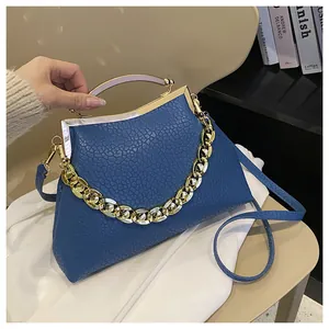 Detail van blauwe handtas van generfd leer met gouden metalen sluiting en ketting