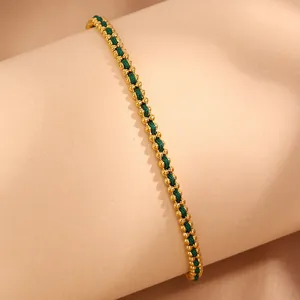 Close-up of gold beaded woven bracelet with green cord on a neutral display stand