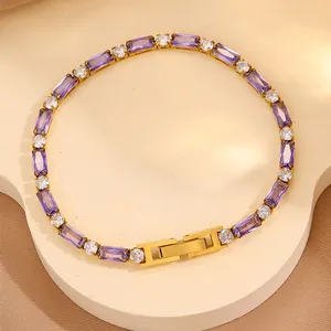 Détail d'un bracelet doré orné de zircons violets et blancs sur un support élégant