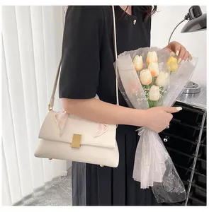Détail du sac crème avec fermoir doré texturé et ruban élégant à motif écossais