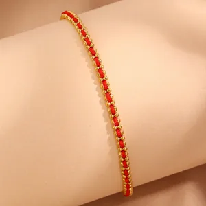 Detailed view of red woven string bracelet with 18k gold plated stainless steel beads