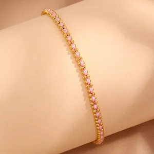 Detail of 18k gold beads woven with pink thread on a braided minimalist bracelet