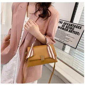 Sac à main en cuir marron avec poignée décorée d'un foulard en soie porté par un mannequin