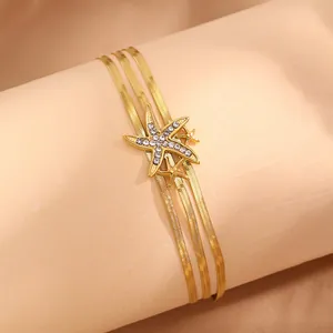 Détail d'un bracelet triple couche doré avec des étoiles de mer ornées de zircons