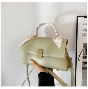 Détail d'un sac à main vert clair en similicuir avec foulard en soie sur la poignée