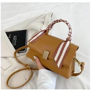 Détail du sac à main en cuir marron avec un foulard en soie enroulé autour de l'anse