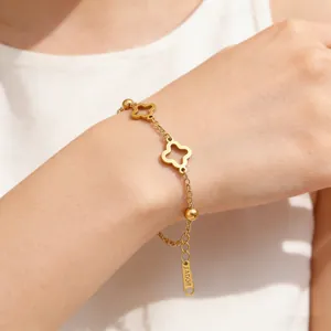 Detail of gold clover bracelet with beads and JADORE tag on wrist
