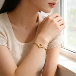 Close-up of golden clover pendant and polished beads on a minimalist stainless steel chain