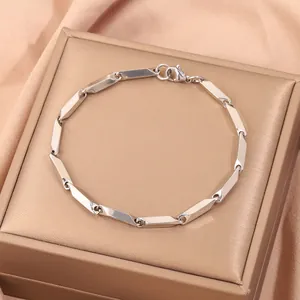 Gros plan d'un bracelet gourmette en acier poli avec fermoir mousqueton sur soie