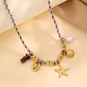 Détail d'un collier tressé coloré avec des pendentifs étoile de mer dorée et perle