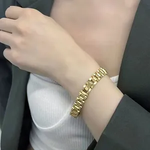 Détail d'un bracelet à maillons en acier inoxydable doré porté au poignet d'une femme