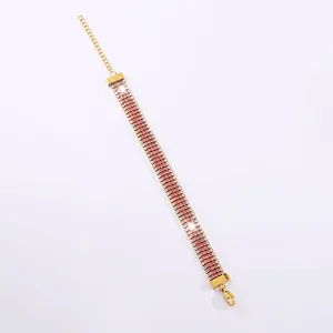 Dettaglio macro di strass rosa e chiusura a moschettone su bracciale in acciaio dorato