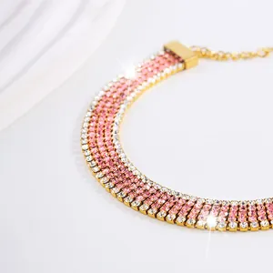 Vista macro di bracciale dorato con cinque file di strass rosa e bianchi brillanti