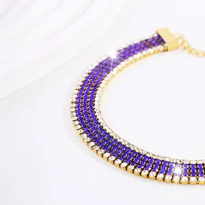 Dettaglio macro di choker dorato con sei file di strass blu e bianchi luccicanti