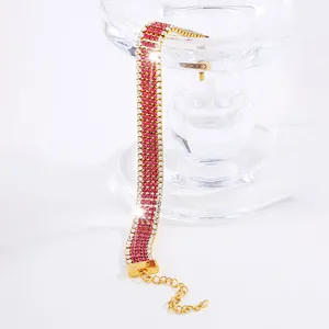Dettaglio macro del bracciale largo dorato con strass rosa e bianchi e catena di estensione
