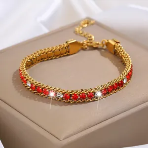 Détail du bracelet en acier titane doré avec cristaux rouges et fermoir mousqueton