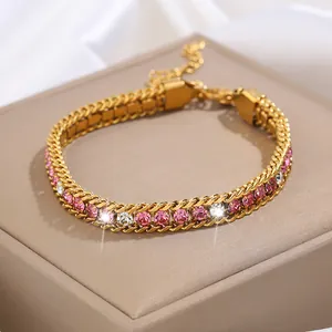 Détail d'un bracelet doré en titane avec double chaîne et strass roses sur coffret cuir