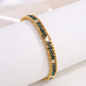 Gros plan du bracelet en chaîne dorée avec pierres précieuses vertes et blanches sur support