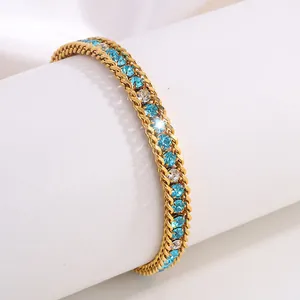 Gros plan d'un bracelet en titane doré orné de cristaux bleus et blancs sur support
