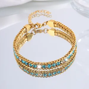 Détail du bracelet doré à double rangée avec cristaux bleus et strass transparents