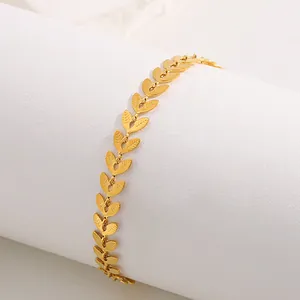 Macro shot of gold leaf charms on a stainless steel bracelet showing fine vein textures
