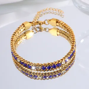 Détail du bracelet doré en acier titane avec cristaux bleus et blancs dans un reflet de miroir