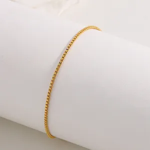 Close-up of a minimalist golden box chain bracelet on a white display pedestal