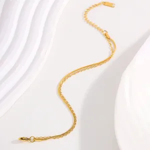Detail of gold double-layer chain bracelet featuring a snake chain and lobster clasp