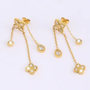 Detail of gold titanium steel earrings with clover motif and dangling zircon tassels