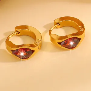 Macro shot of gold-plated hoop earrings featuring drop-shaped red zircon gemstones