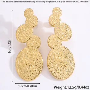 Détail macro de boucles d'oreilles dorées style océan avec texture martelée et tailles