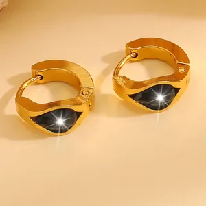 Macro detail of gold hoop earrings with teardrop black stone and starburst inlay