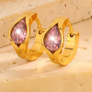Luxury gold hoop earrings with pink pear-cut zircon on textured stone background