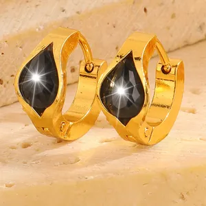 Macro shot of gold teardrop earrings with faceted black gemstones on a stone base
