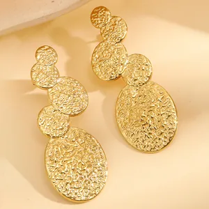 Détail de boucles d'oreilles en acier inoxydable doré avec texture martelée style océan