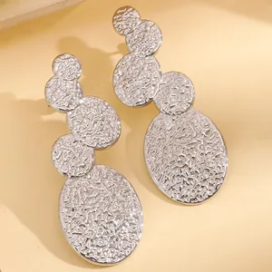 Détail de boucles d'oreilles argentées avec texture martelée et disques ovales polis