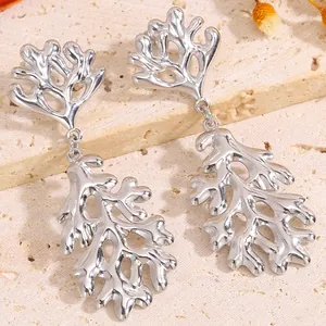 Gros plan de boucles d'oreilles corail style océan avec finition argent poli sur pierre