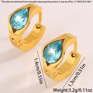 Detail view of gold huggie earrings with blue zircon stones and size measurements