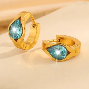 Macro detail of gold-plated hoop earrings featuring a vibrant blue teardrop zircon stone